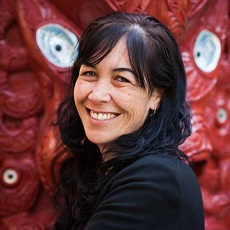 head shot of Professor Rawinia Higgins in front of carved panel of wharenui