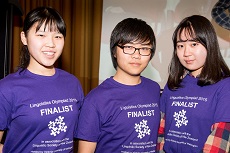 Three students in purple T-shirts smiling (Linguistics Olympiad Winners)
