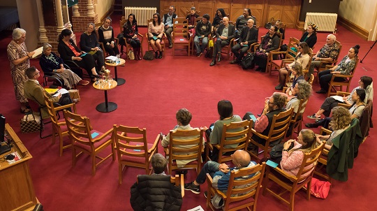 The group of 30 guests from above sitting in a circle as if around a campfire.