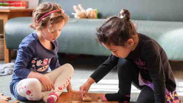 20 Hours Eerly Childhood Education – Two young girls play with a wooden puzzle together.