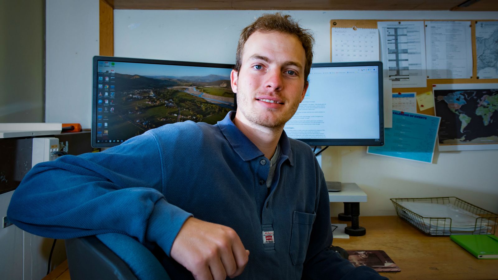 Leo sits at his desk, turned towards the camera, with his computer behind him. 