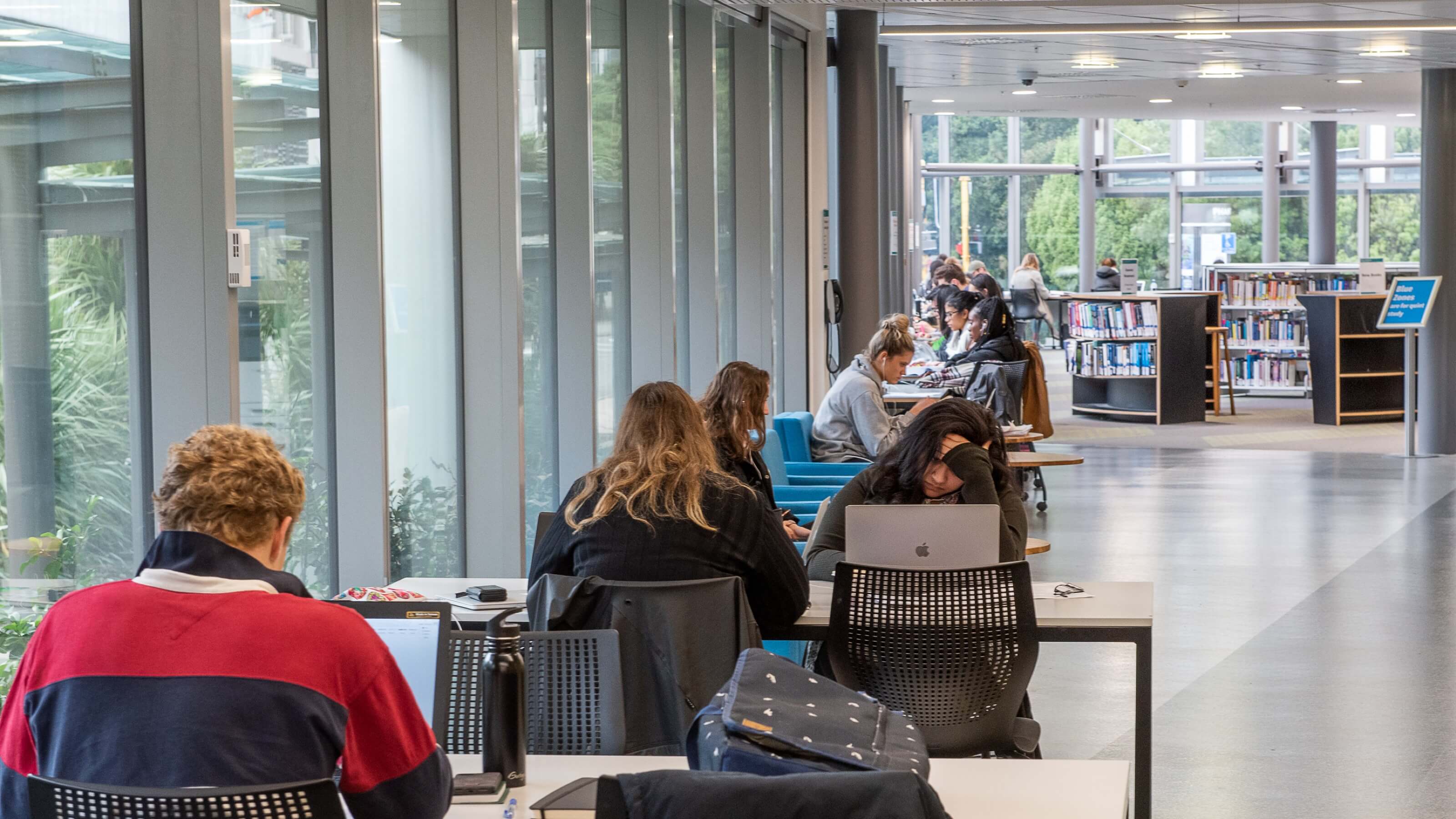 Students studying at various desks in the library.