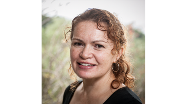 A profile image of a woman standing in front of tall grass.