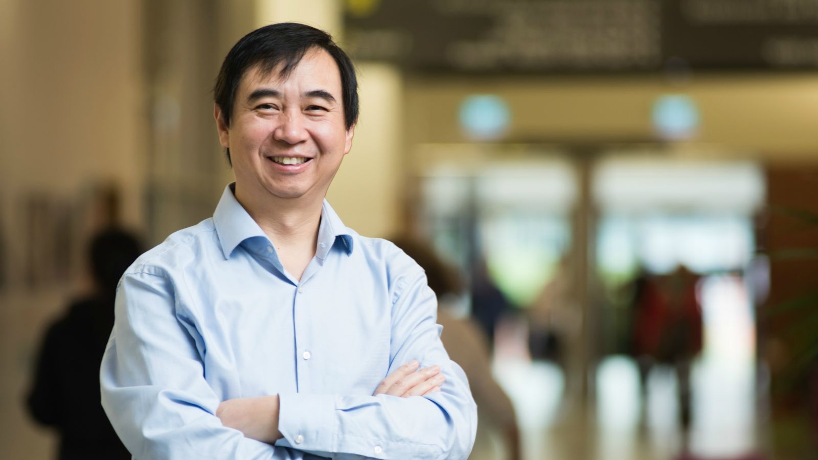 Man stands smiling with arms folded.