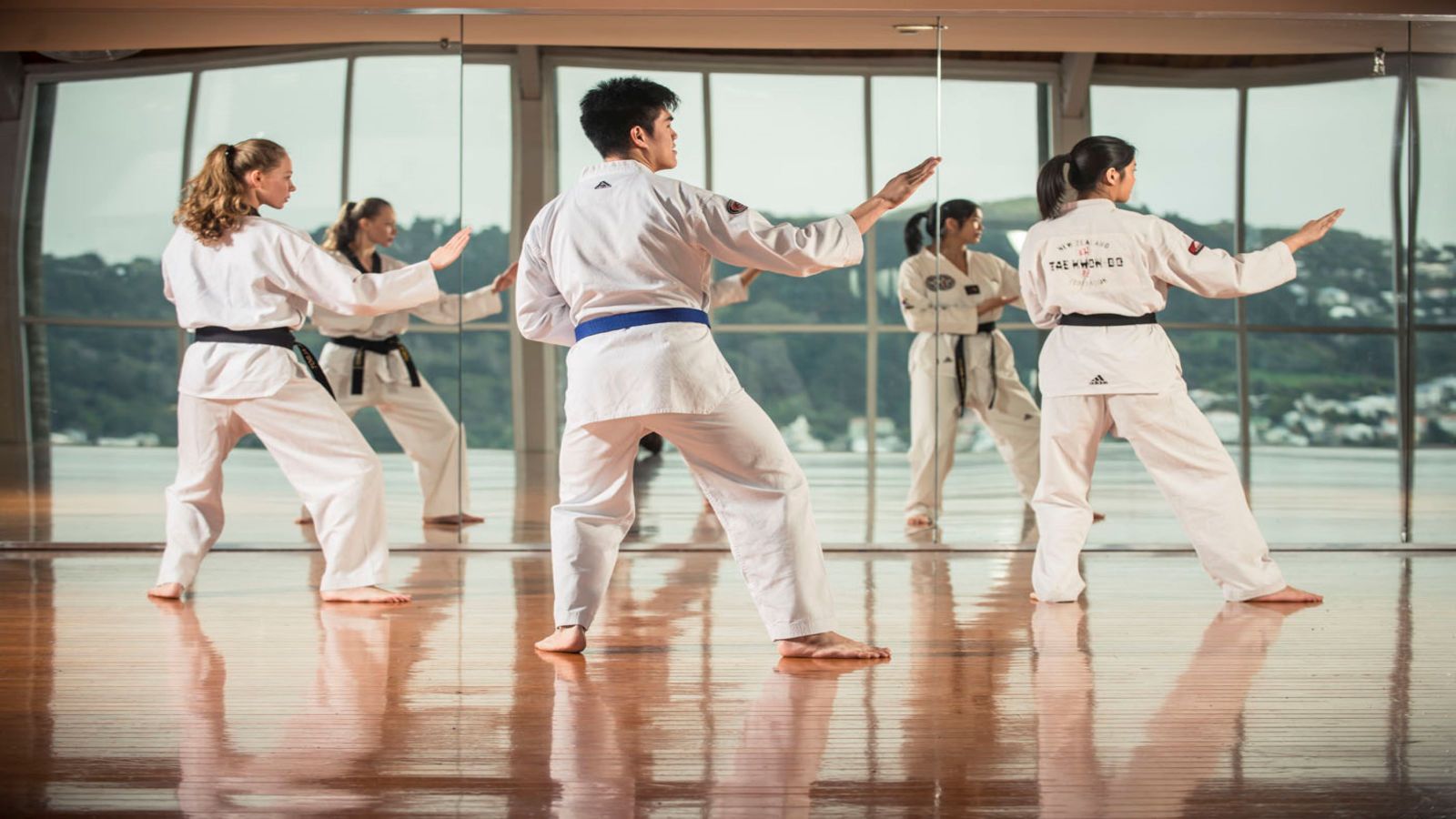 Three students standing in front of window during taekwondo training
