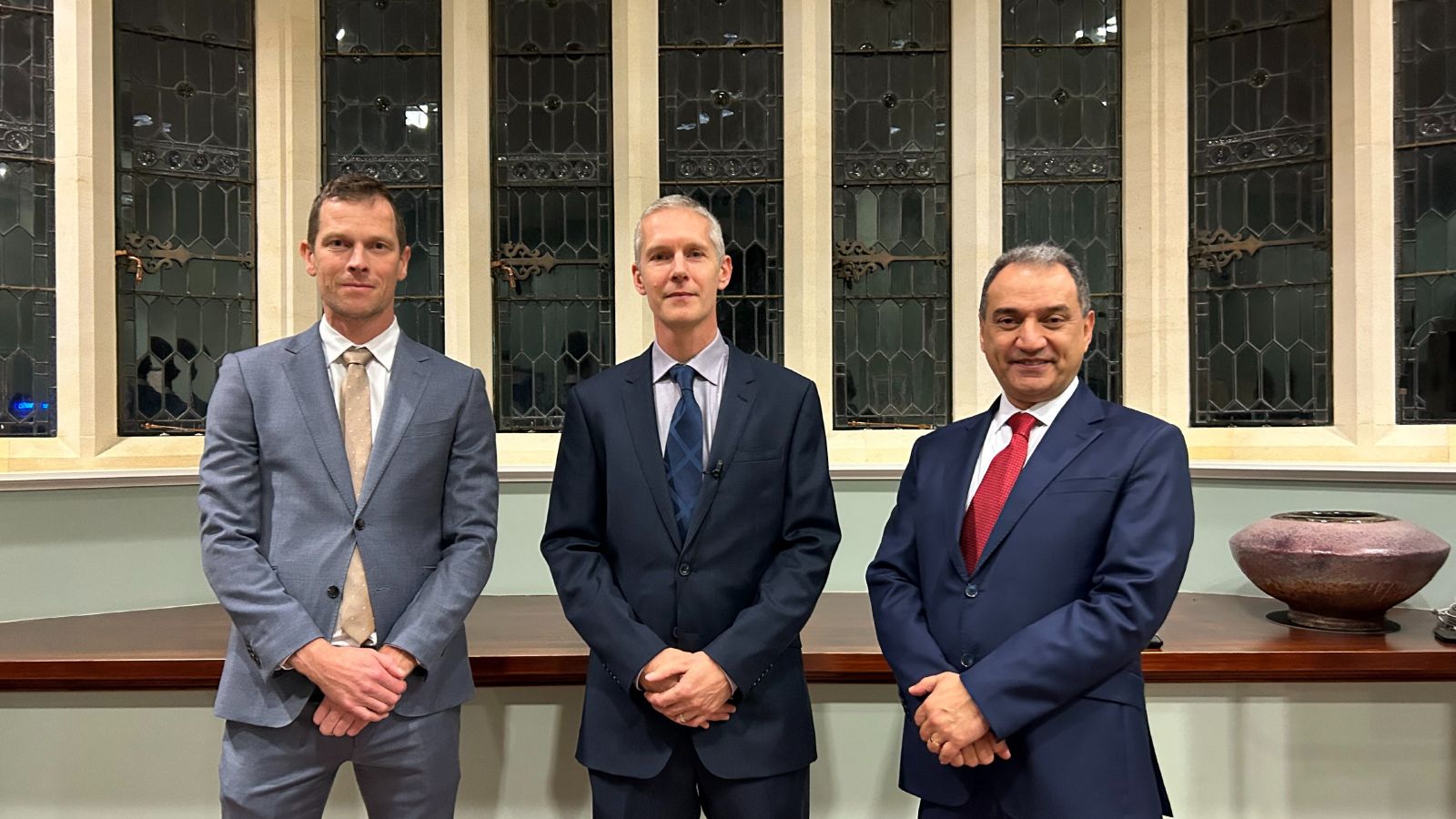 Nicholas Golledge, dressed in a suit, flanked by two other suited men on the evening of his inaugural lecture