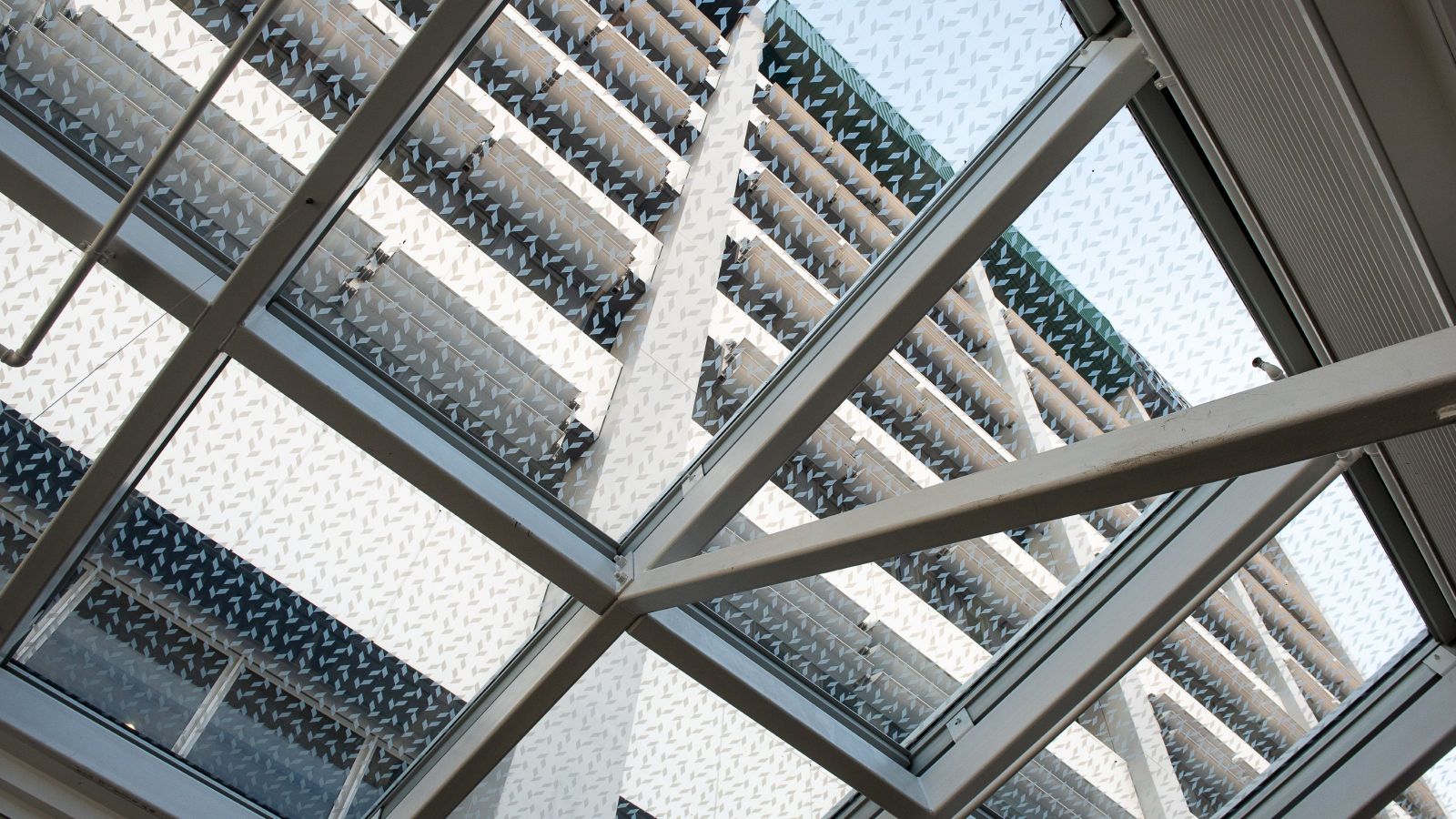 Looking up through a patterned glass ceiling at the outside of a building. 