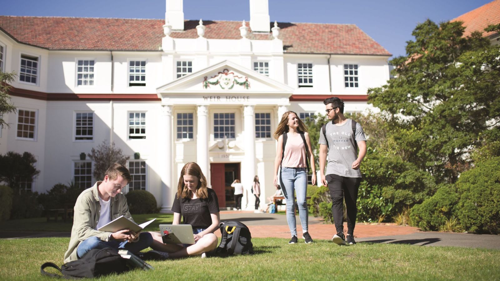 Students sitting on lawn and waking in front of accommodation building