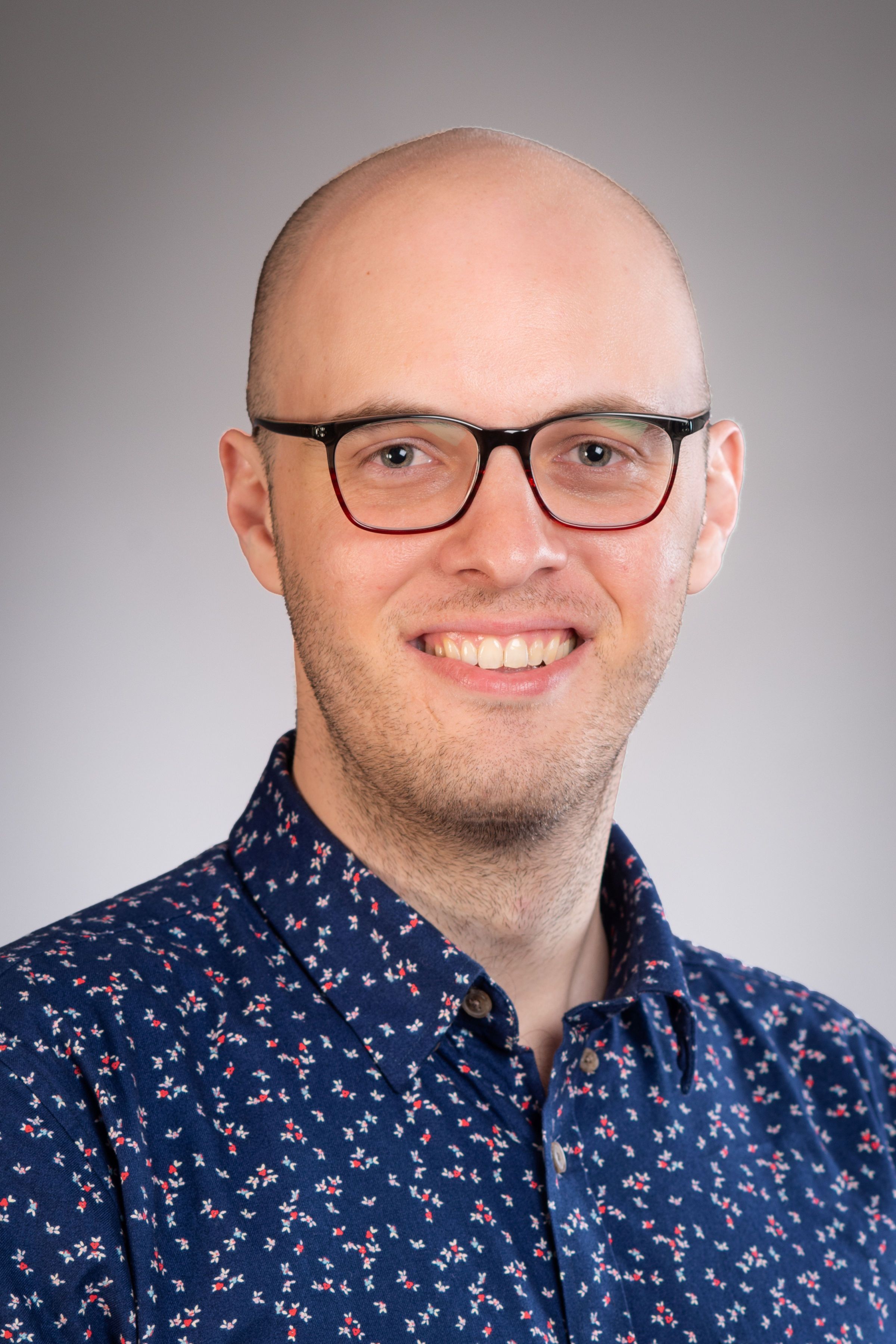 Dr James Wenley in front of a grey background.