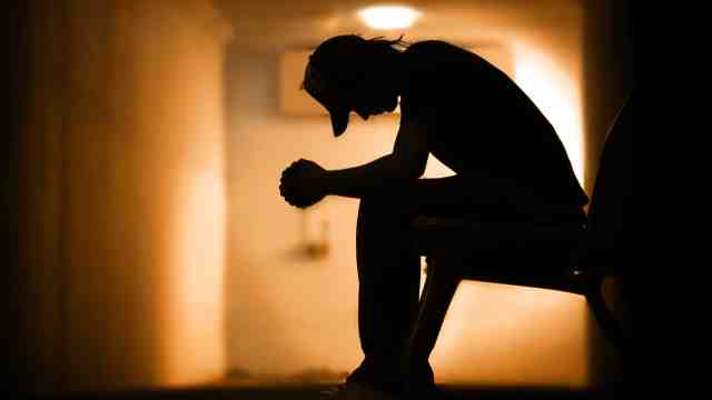 Suicide bereavement – an image of a silhouetted image of a man crouched against a wall.