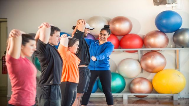 Trainer corrects position of student during stretching