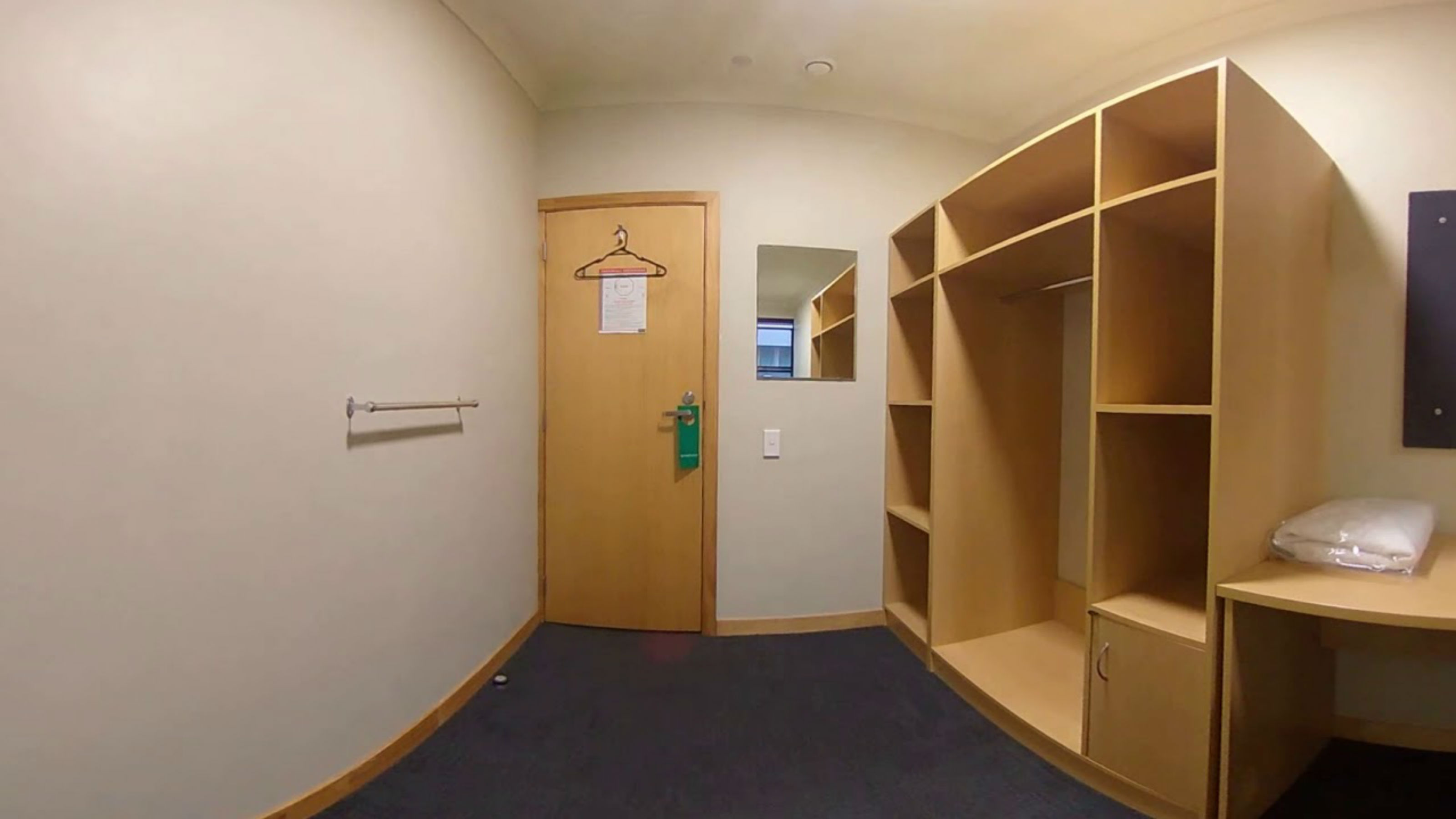 Image of an empty from the inside facing a closed door and empty wardrobe.