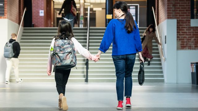 A woman and girl hold hands walking