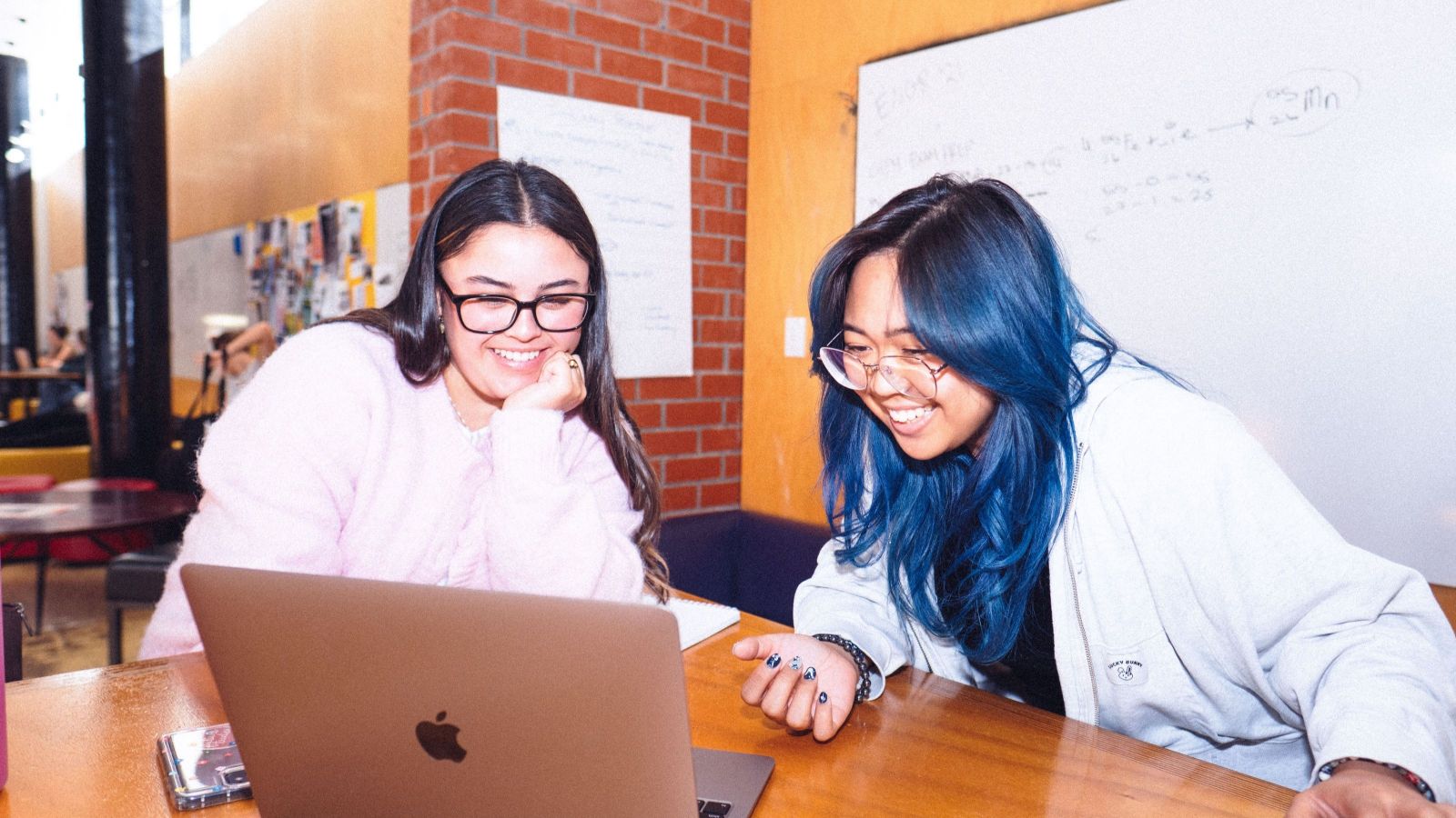 Two smiling students looking at a laptop