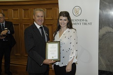 Samantha wearing a white shirt being presented her certificate by  Rt Hon David Carter