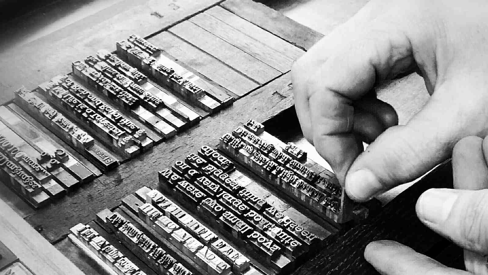 The Printer's hands insert a space into the locked up metal type waiting to be printed.