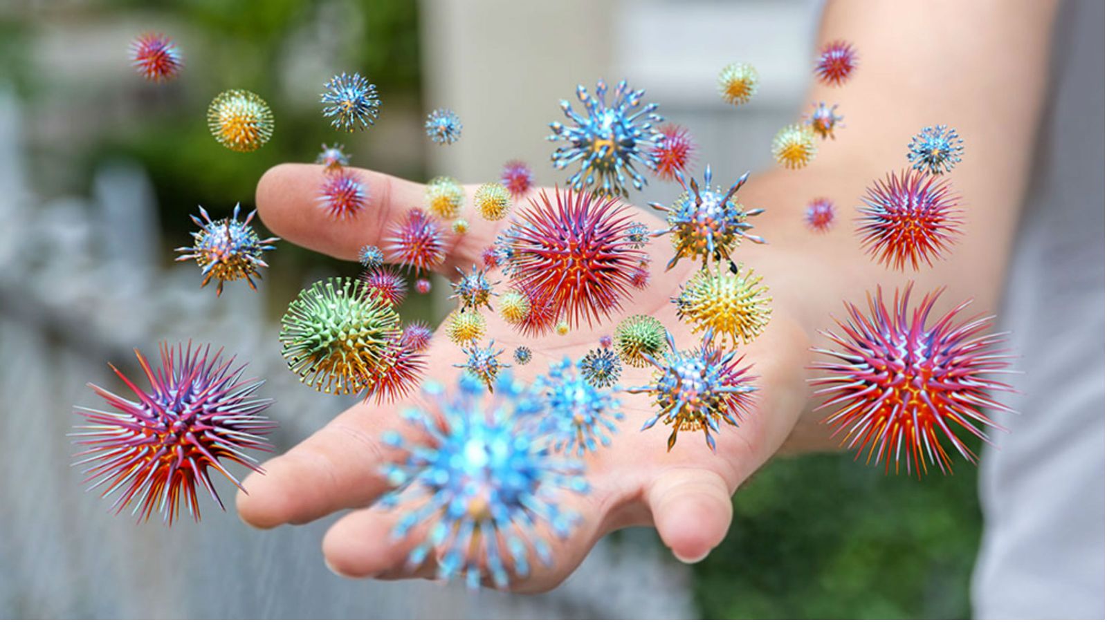 Dozens of colourful spikey spheres orbiting an outstretch human hand.
