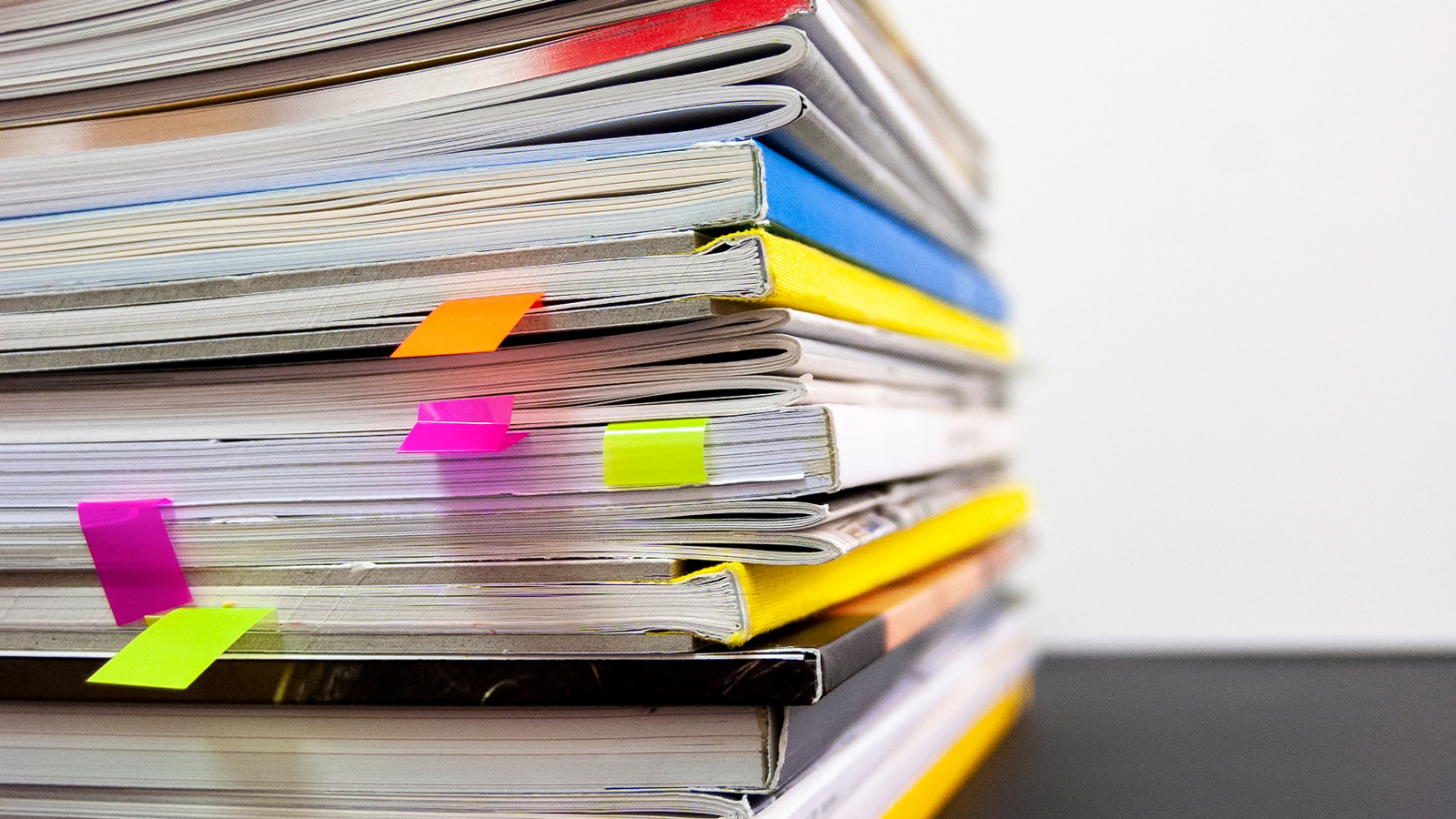 A stack of journals with some coloured bookmarks