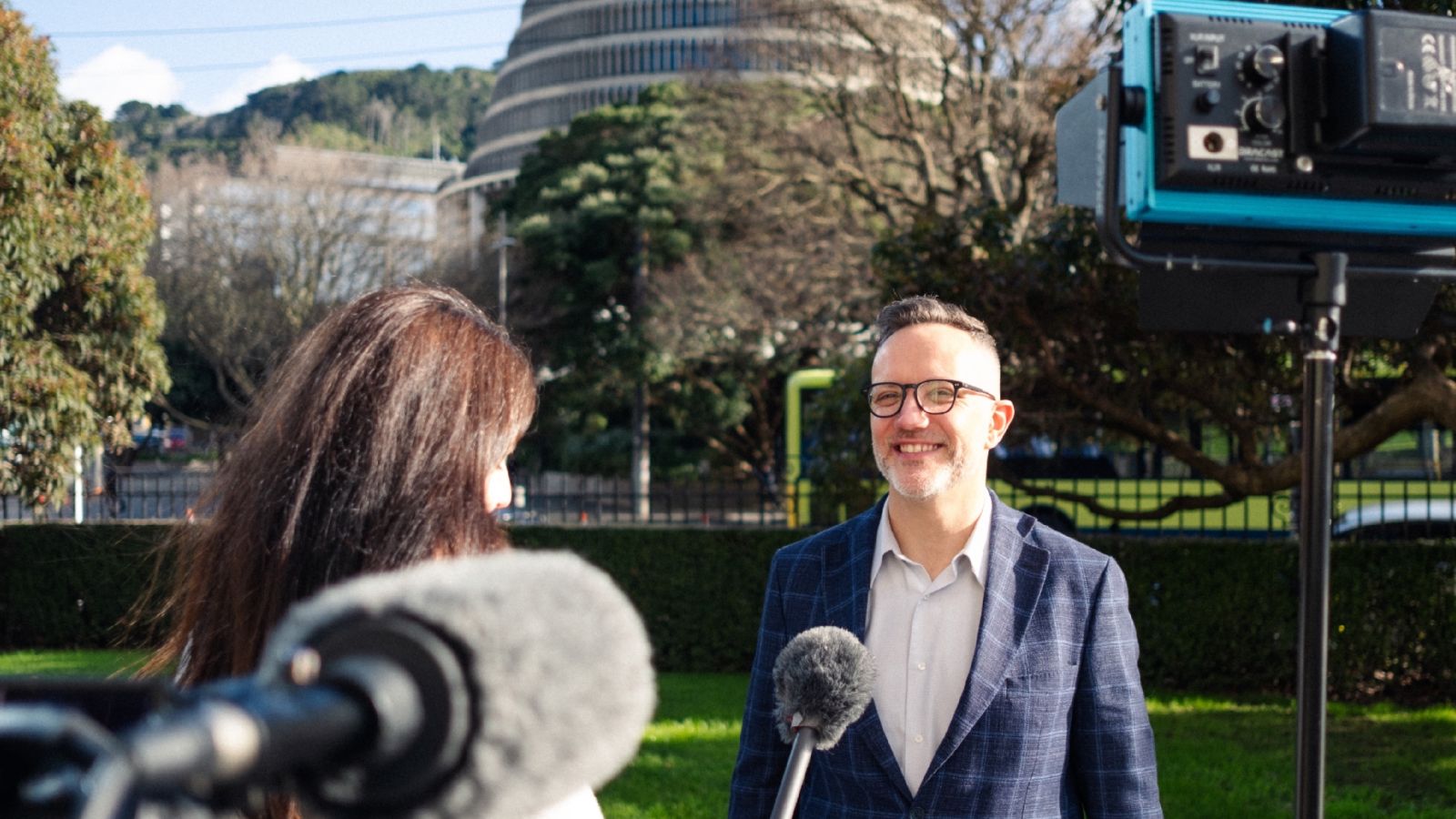Jeff being interviewed by a women in front of the beehive in Wellington