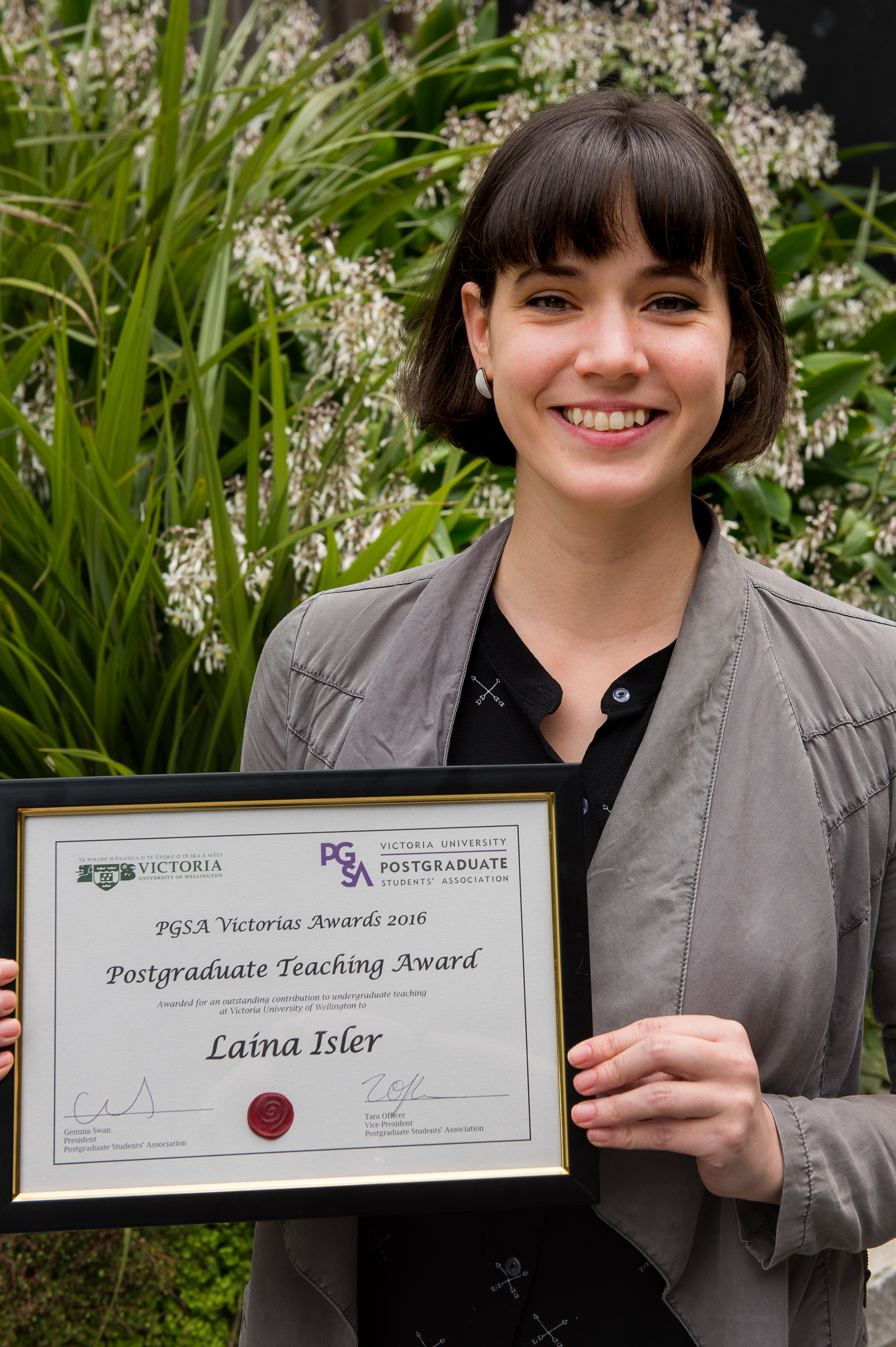 An image of Laina Isler holding her Postgraduate Teaching Award "PGSA Victoria's award 2016"