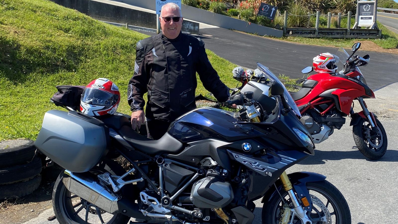 Paul McGilvary in black motorcycle clothing standing behind a black motorcycle