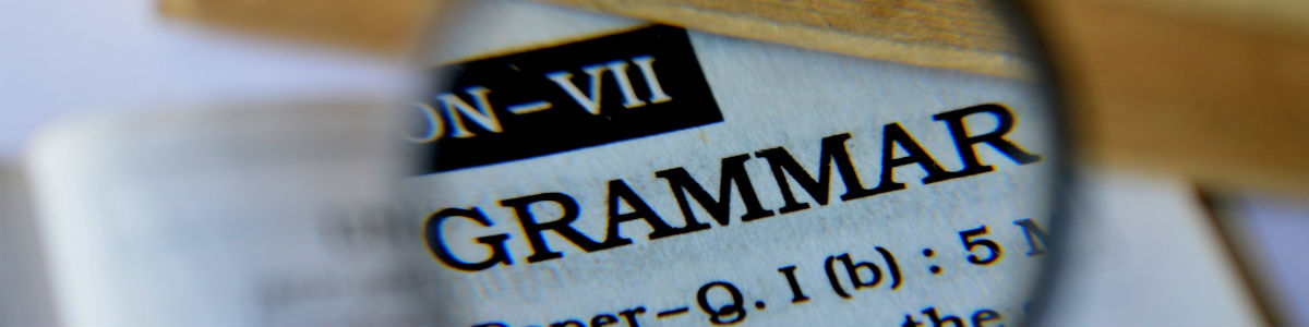 Banner image – A magnifying glass is Zoomed in on the word “Grammar” in a dictionary.