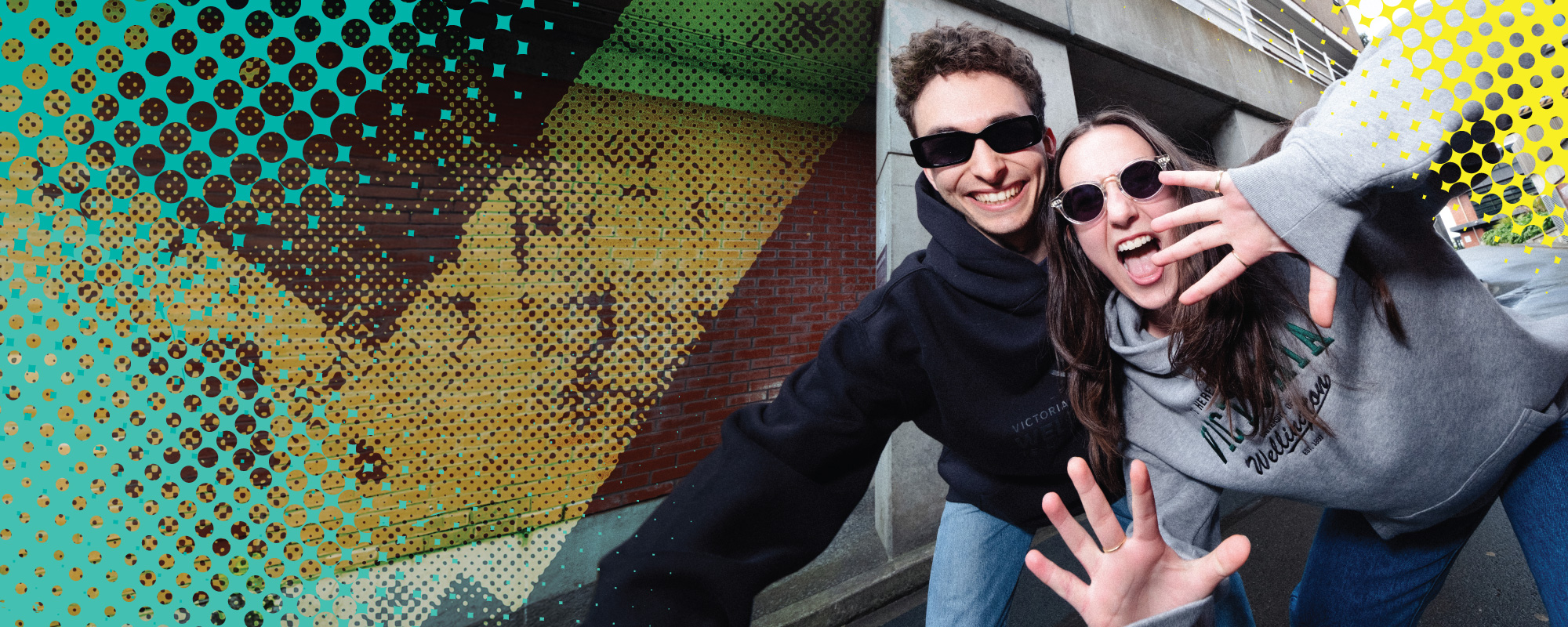 two students smiling wearing hoodies and sunglasses