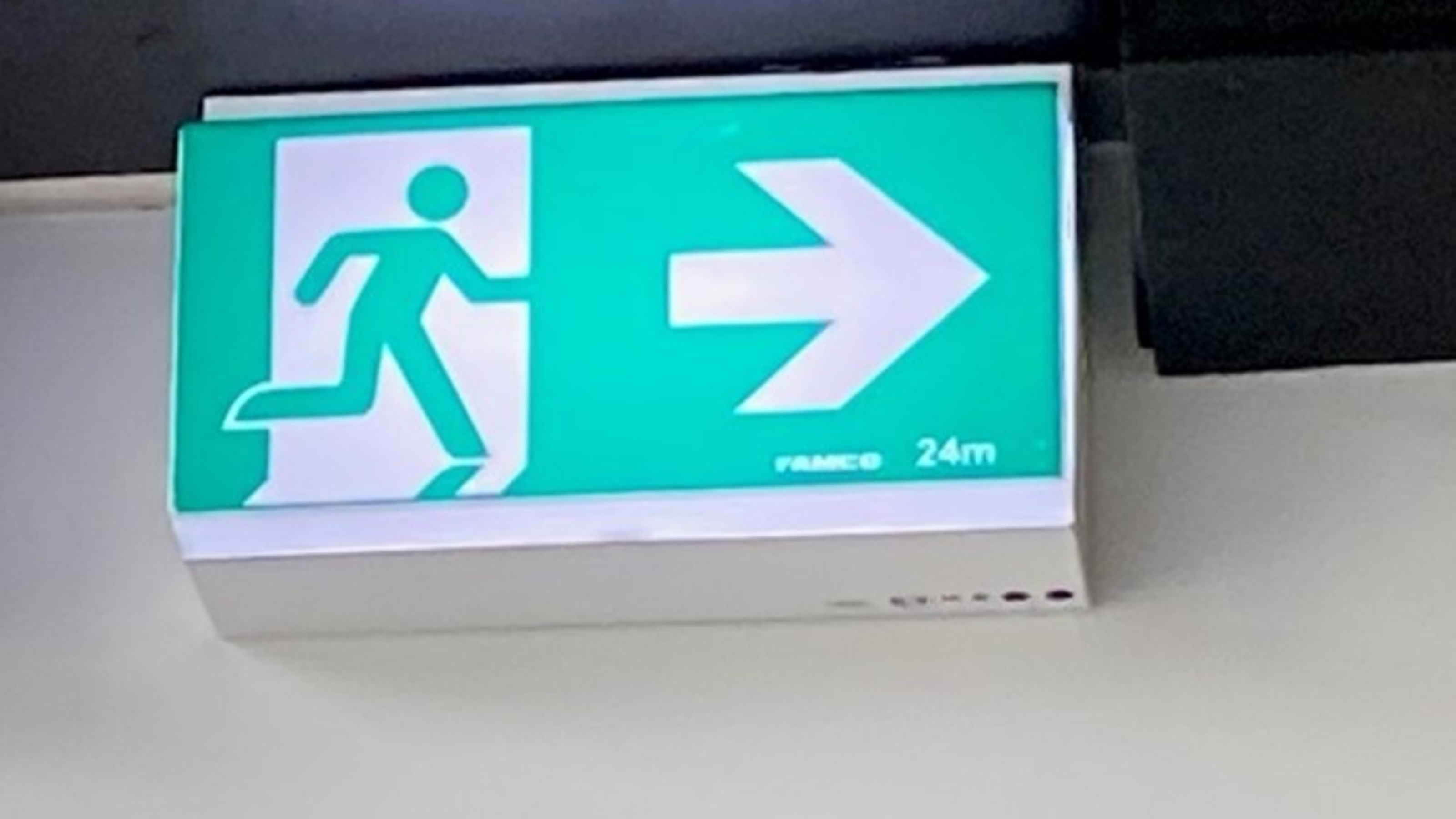 The sign for emergency exist is green and white and has a person symbol and an arrow to show which way to evacuate