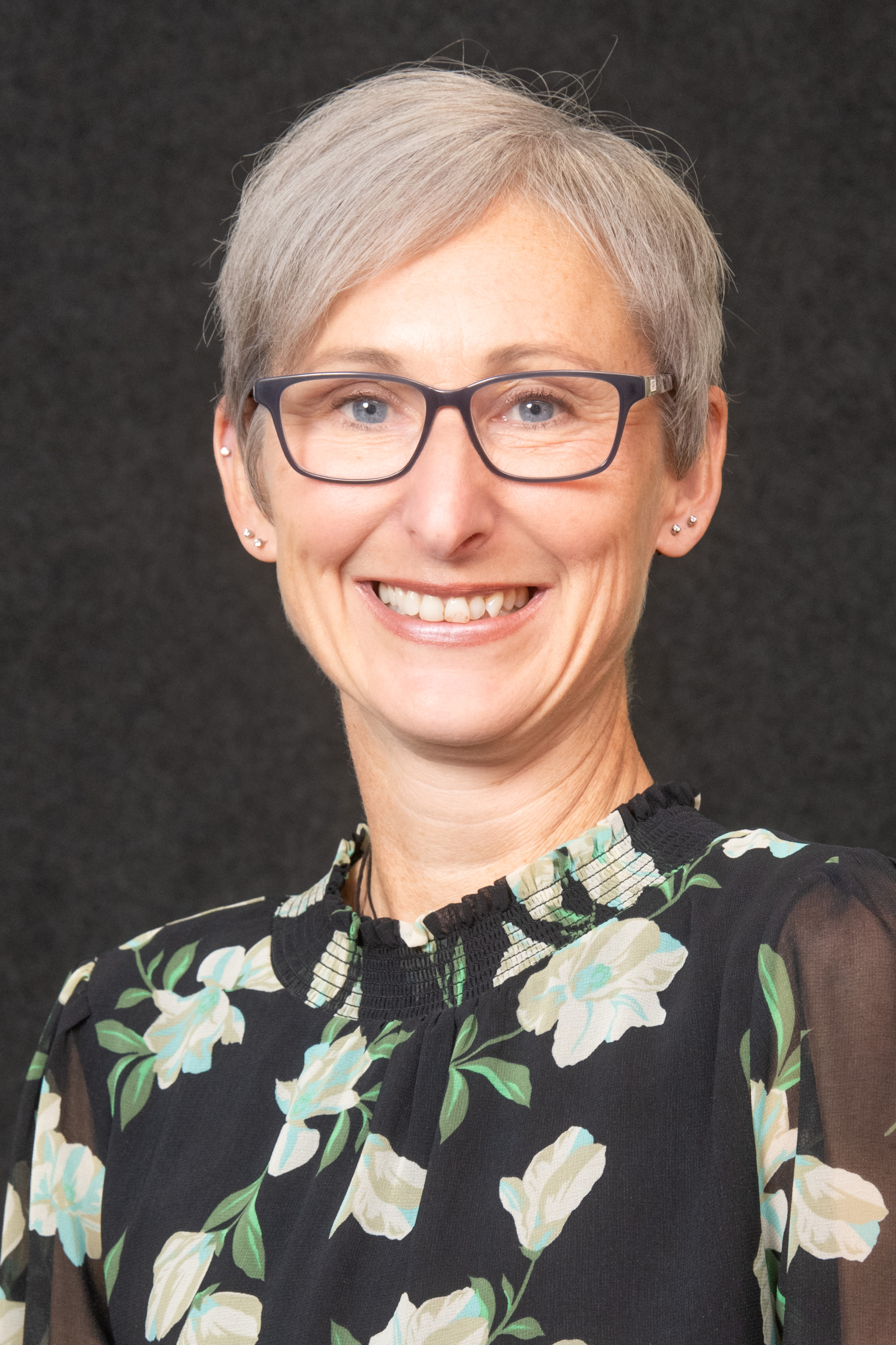 Associate Professor Caz Hales in front of black background.