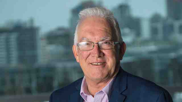 A profile photo of Professor Richard Furneaux, with a dim cityscape in the background