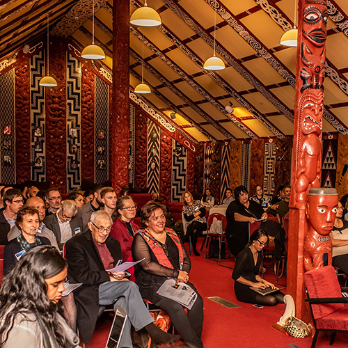 A crowd in a marae listen to a speaker at the Māori Data Futures hui.