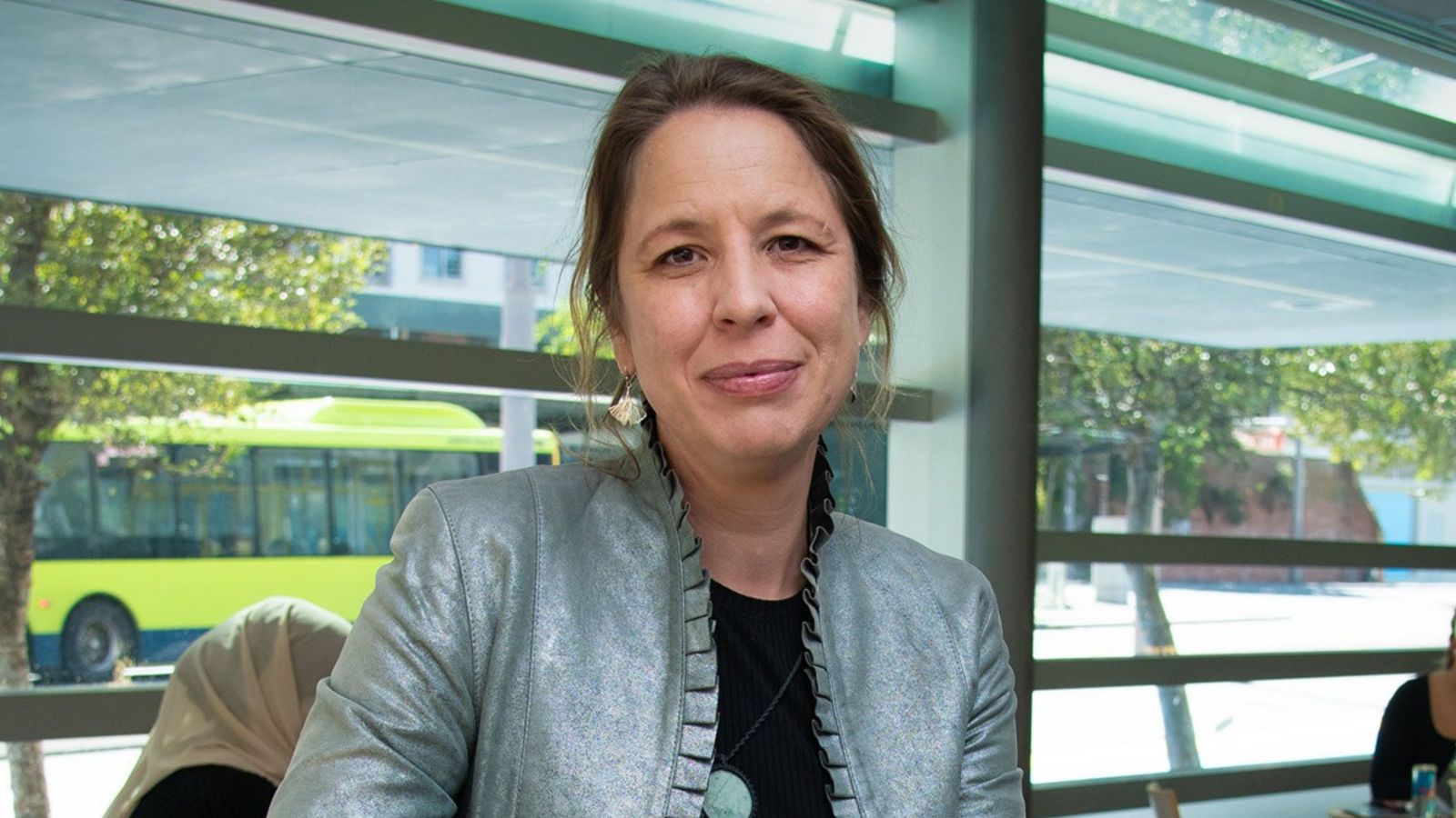 A photo of a middle aged pakeha woman in a silver jacket looking at the camera.