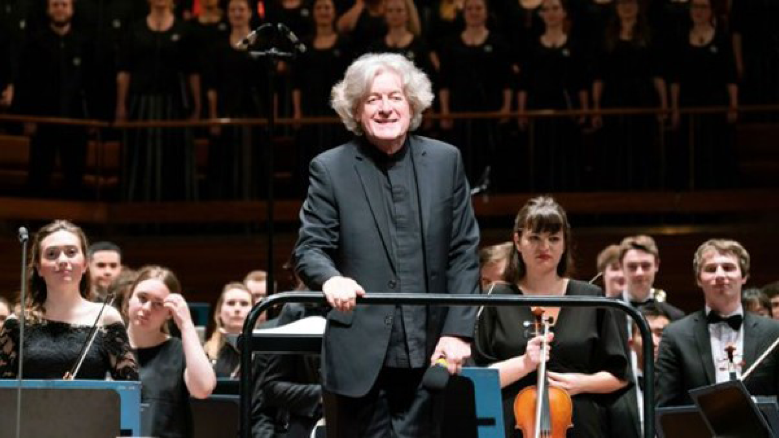 Conductor James Judd stands in front of an orchestra