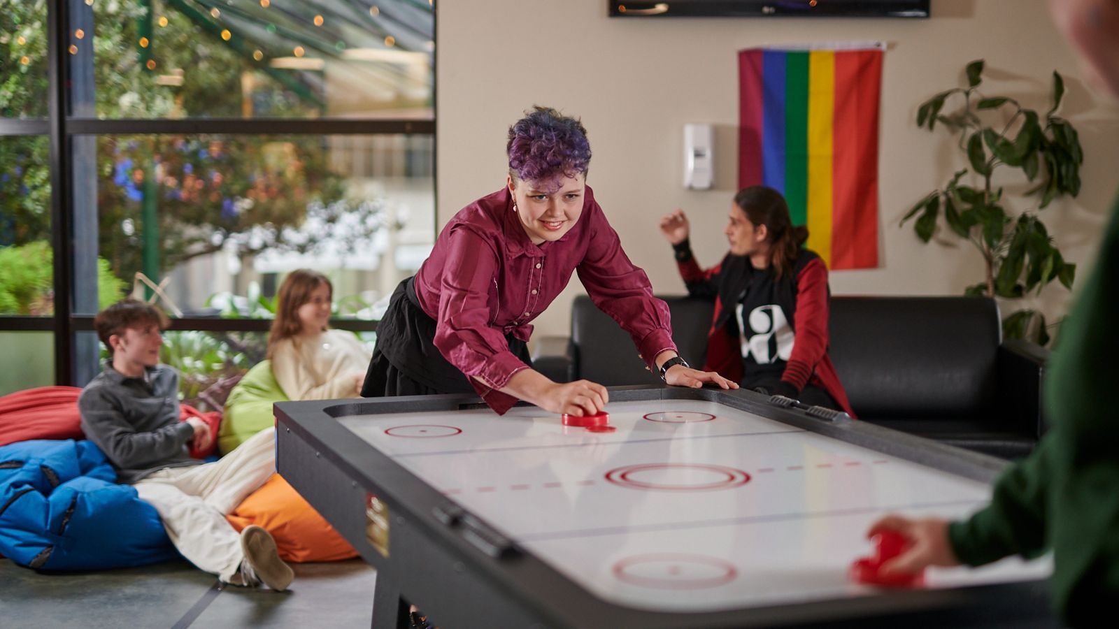 Residents playing air hockey and hanging out in the common room at Joan Stevens Hall