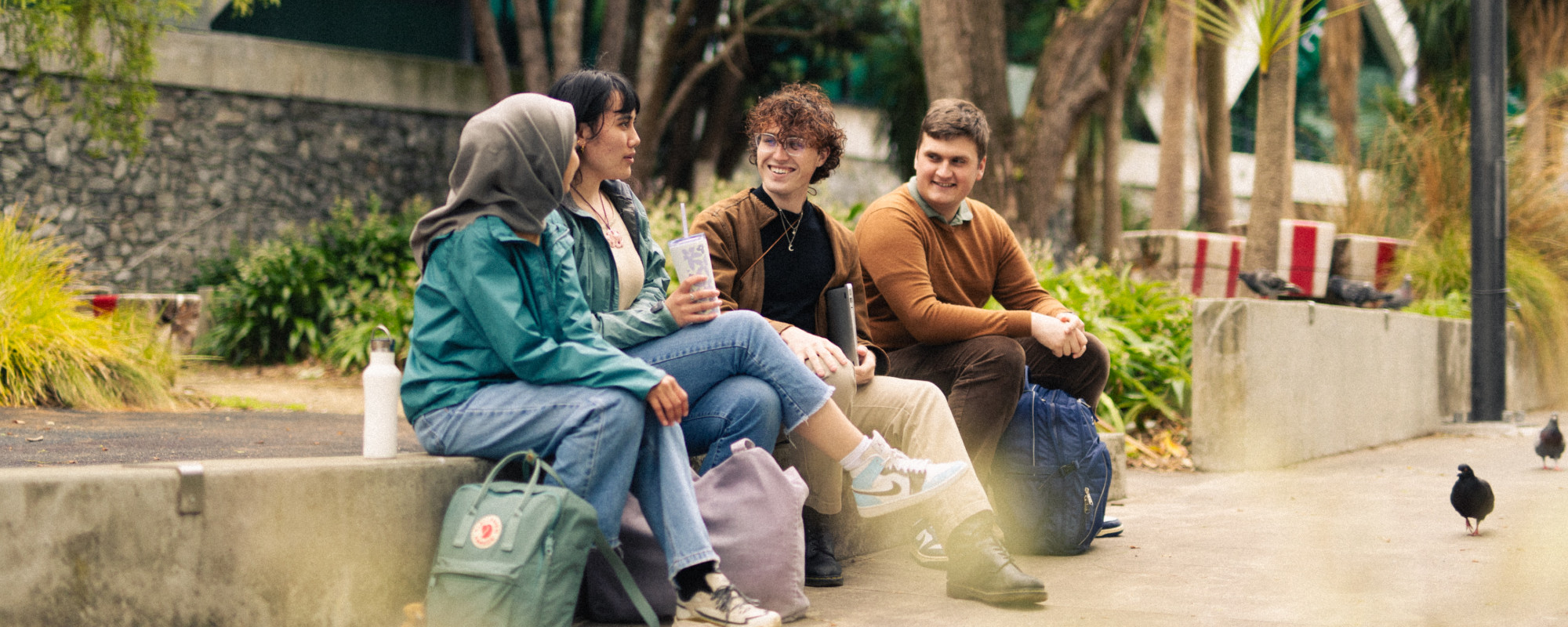 Four architecture students sitting in central Wellington, with pigeons in the foreground