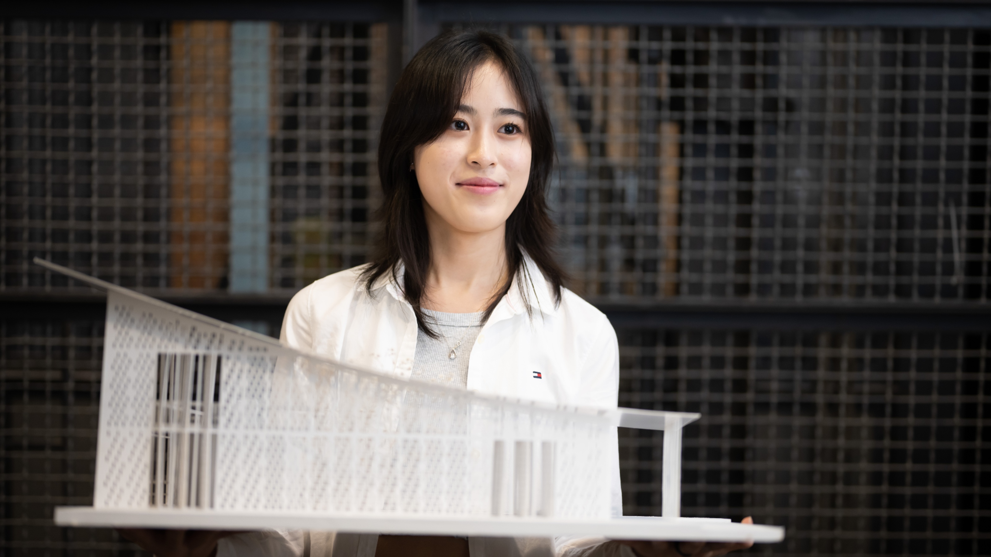 Image of Danbie Bong holding architectural model and smiling