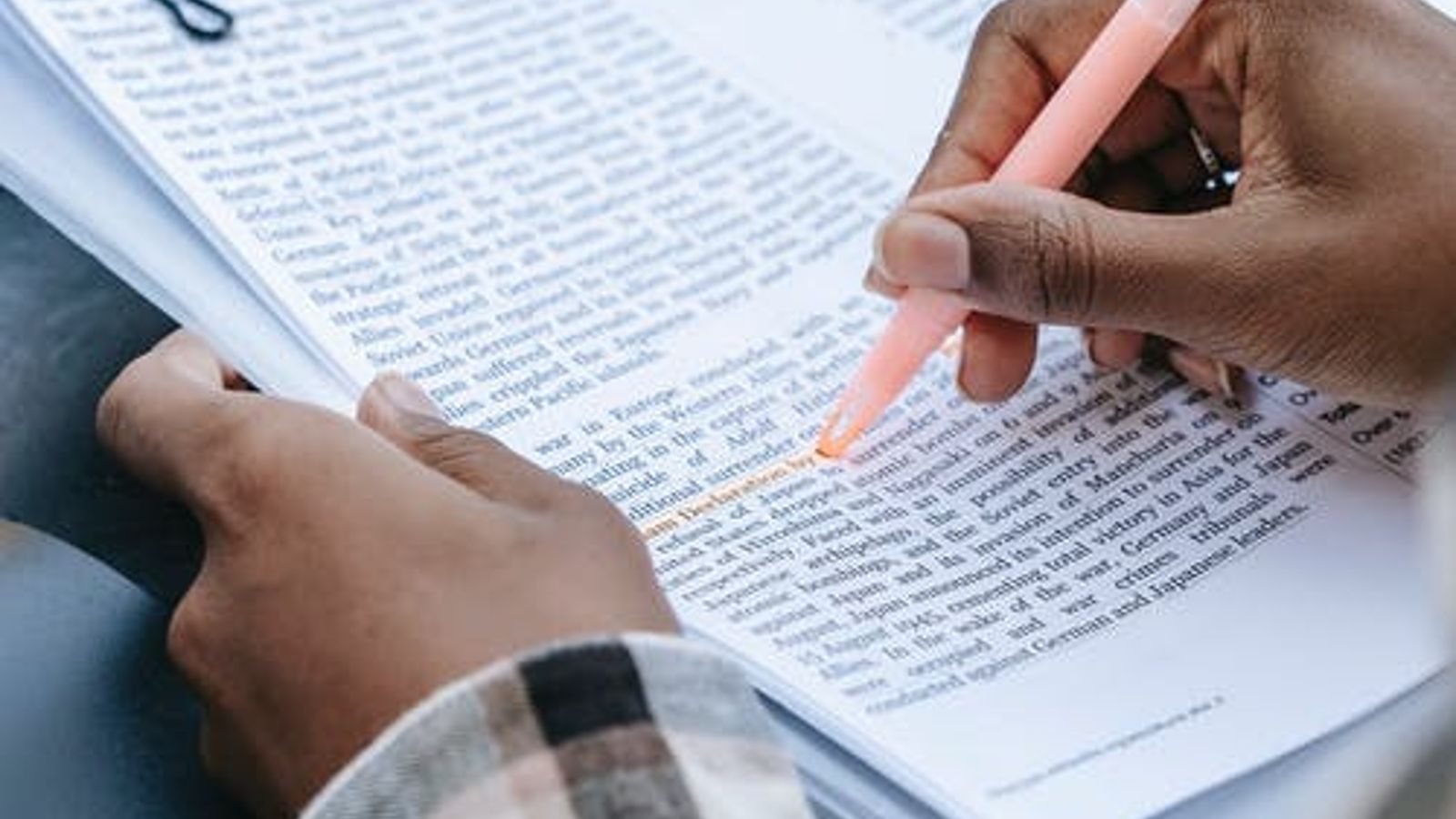 A hand is seen highlighting a textbook