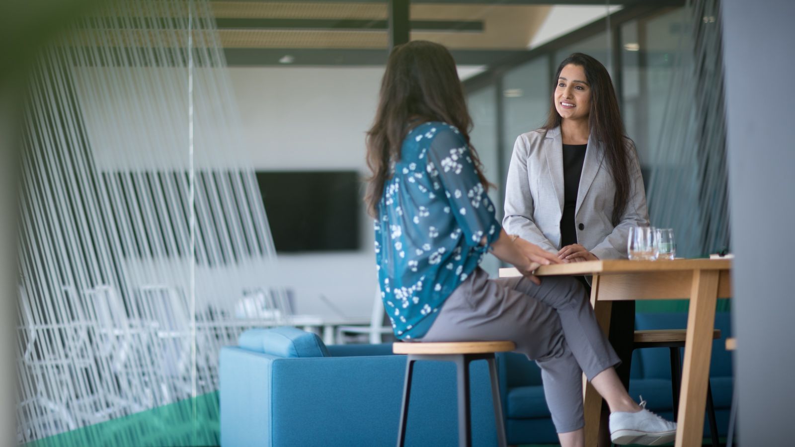 Two women talking at a high table in their office