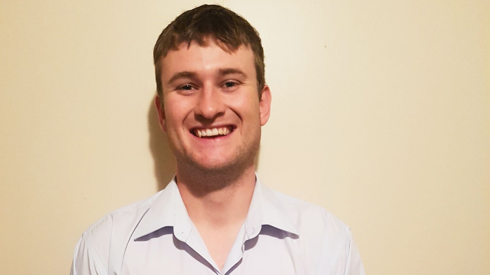 Head and shoulders portrait of Brad. Brad wears a white shirt and smiles at the camera.