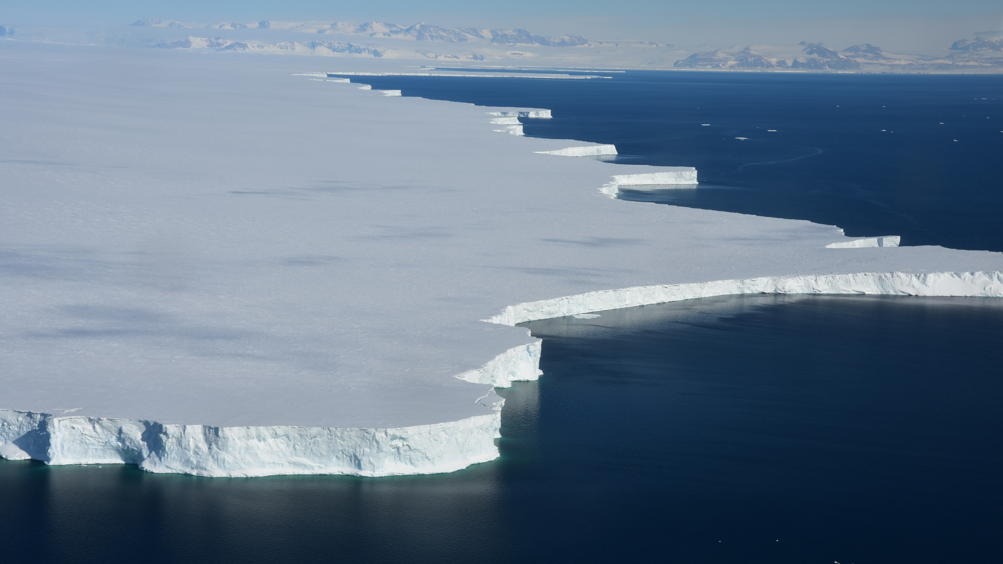 Aerial shot of huge ice sheet next to dark blue ocean