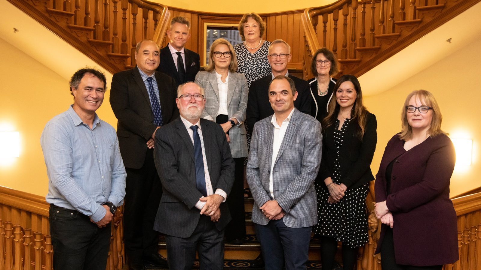 A group of academics formally dressed and standing in a stairwell