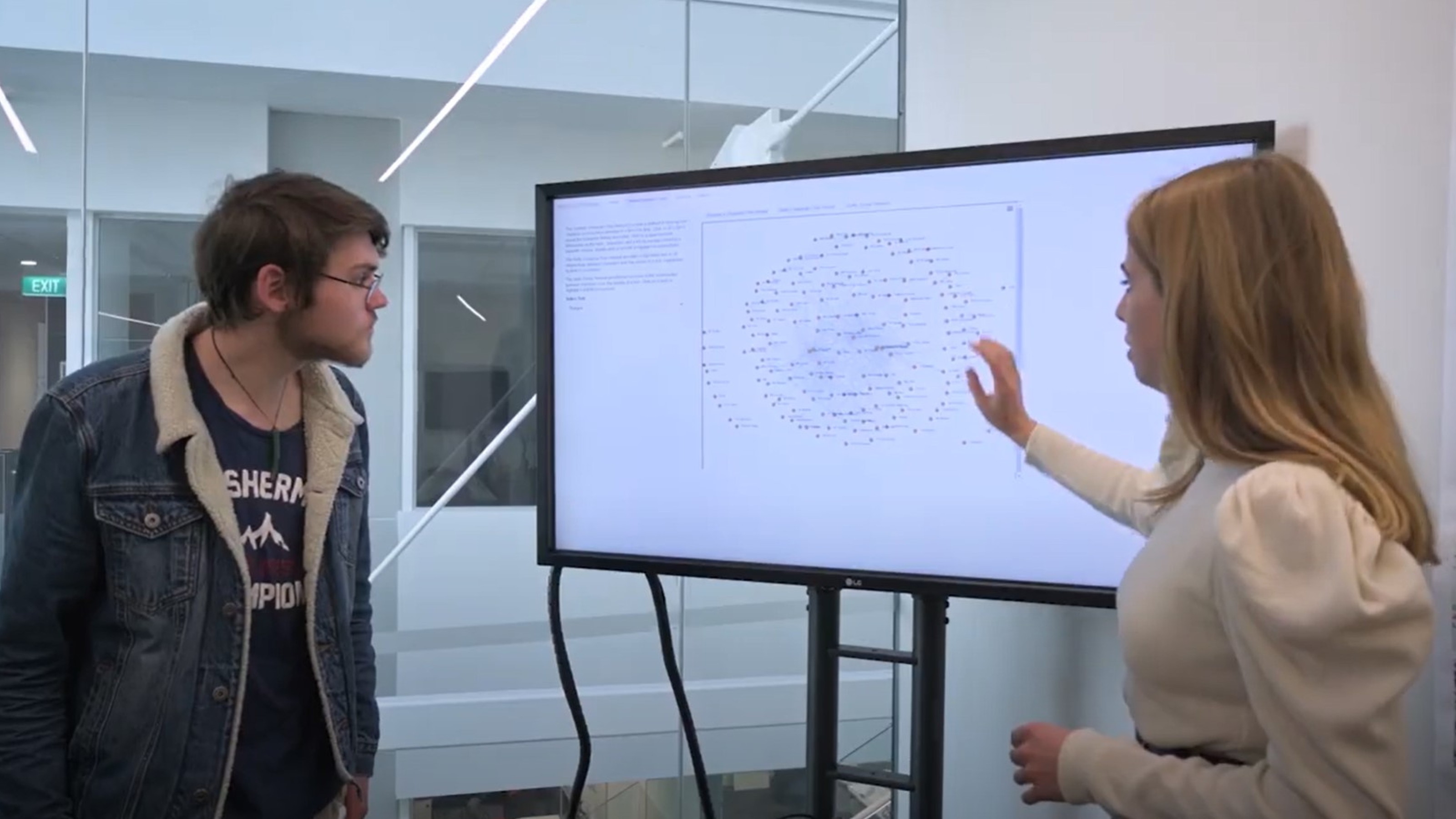 Two students examine word cloud on electronic whiteboard