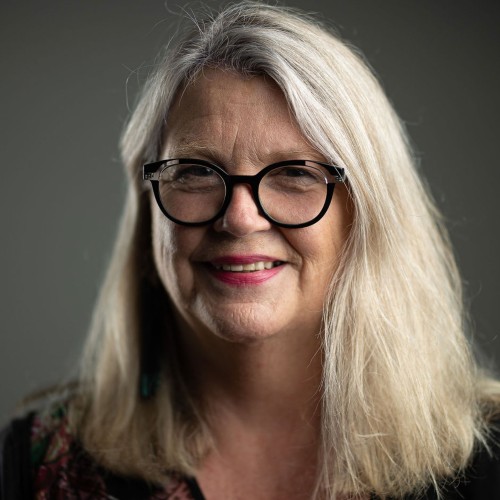 Smiling woman with white hair and round glasses