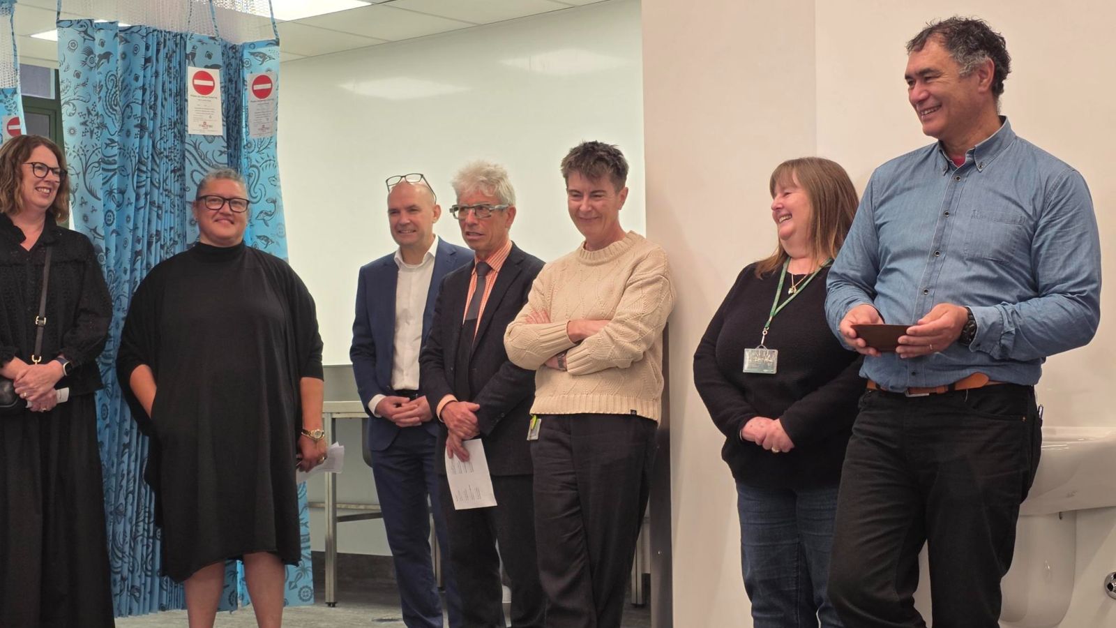 Group of people standing in a room listening to a blessing