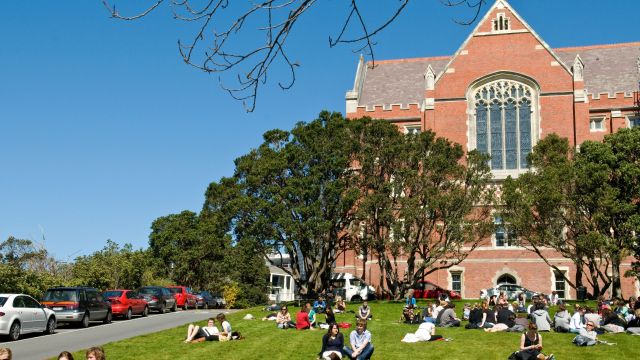 Students sitting on the grass outside a university building