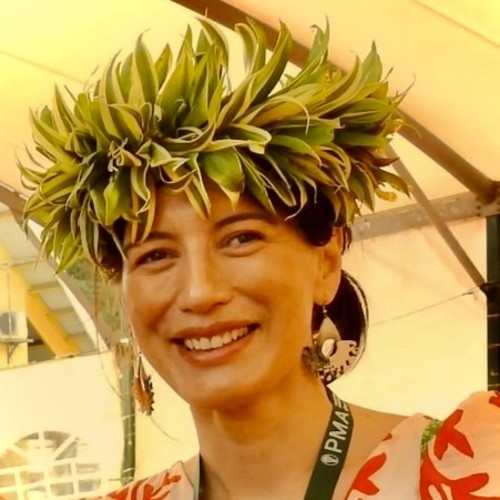 Pacific woman with black hair tied up in a low bun wearing a head piece. 