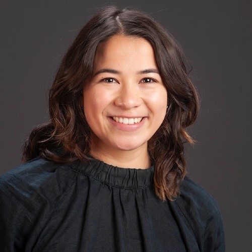 Asian women with brown curly hair smiling wearing a black shirt.