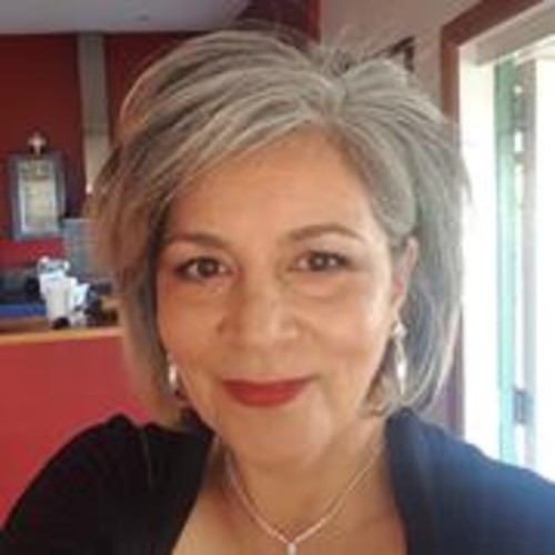 Pacific woman with grey short shair wearing red lipstick smiling.