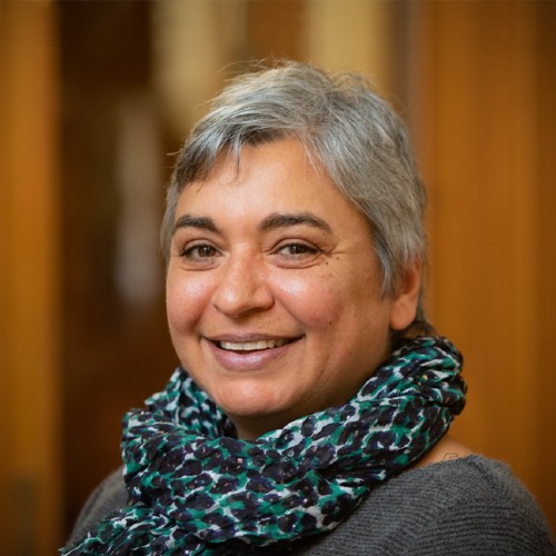 Woman with short grey hair smiling wearing a green scarf.