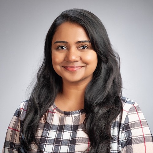 Sri Lakan woman with long black hair smiling wearing a cross-checkered shirt.